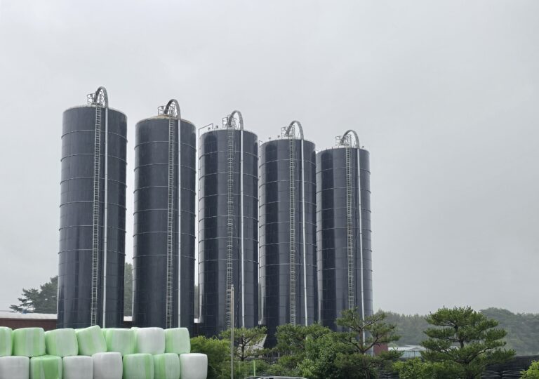 Towering black storage tanks stand in formation at the facility, designed to hold and stabilize liquid livestock manure before processing. These silos are the first stage in transforming organic waste into high-value biochar — managing volume, odor, and consistency with industrial-scale precision.
